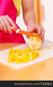 Woman young housewife in kitchen at home slicing fresh orange fruits on cutting board for salad or juicing. Healthy eating, cooking, raw food, dieting and people concept.. Woman housewife in kitchen cutting orange fruits