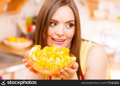 Woman young housewife in kitchen holds bowl full of sliced orange fruits preparing to make fresh juice or salad. Healthy eating, cooking, vegetarian food, dieting and people concept.. Woman holds bowl full of sliced orange fruits