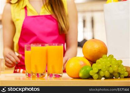 Woman young housewife in kitchen making fresh orange juice. Healthy eating, vegetarian food, dieting and people. Woman with fresh fruits and juice in kitchen