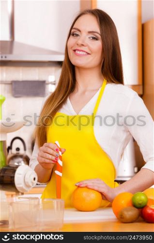 Woman young housewife in kitchen with fruits and juicer preparing to make fresh juice, cutting with knife grapefruit. Healthy eating, cooking, vegetarian food, dieting and people concept.. Woman in kitchen preparing fruits for juicing