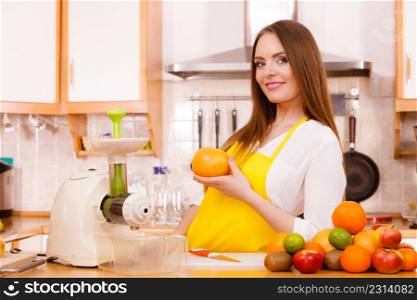 Woman young housewife in kitchen with fruits and juicer preparing to make fresh juice. Healthy eating, cooking, vegetarian food, dieting and people concept.. Woman in kitchen preparing fruits for juicing