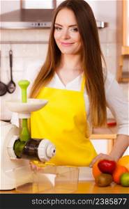Woman young housewife in kitchen with fruits and juicer preparing to make fresh juice. Healthy eating, cooking, vegetarian food, dieting and people concept. Woman in kitchen preparing fruits for juicing