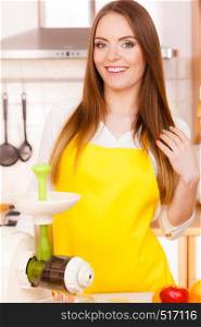 Woman young housewife in kitchen with fruits and juicer preparing to make fresh juice. Healthy eating, cooking, vegetarian food, dieting and people concept. Woman in kitchen preparing fruits for juicing
