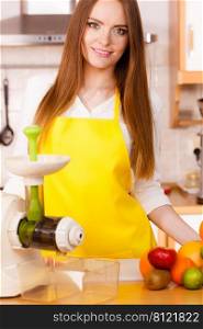 Woman young housewife in kitchen with fruits and juicer preparing to make fresh juice. Healthy eating, cooking, vegetarian food, dieting and people concept. Woman in kitchen preparing fruits for juicing 