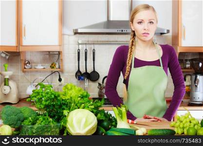 Woman young housewife in kitchen with many green leafy vegetables, fresh garden produce organically grown on counter. Healthy eating, cooking, vegetarian food, dieting and people concept.. Woman housewife in kitchen with green vegetables