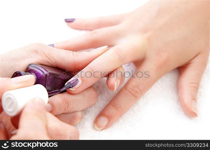 womans finger nails having purple varnish applied on white towel