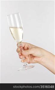 Womans hand holding a glass of white wine