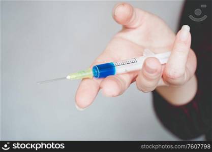 Womans hand holding a syringe