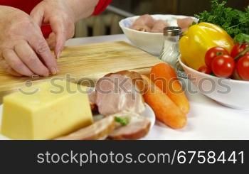 Women&acute;s hands cooking rolls of chicken breast, add bacon and cheese.