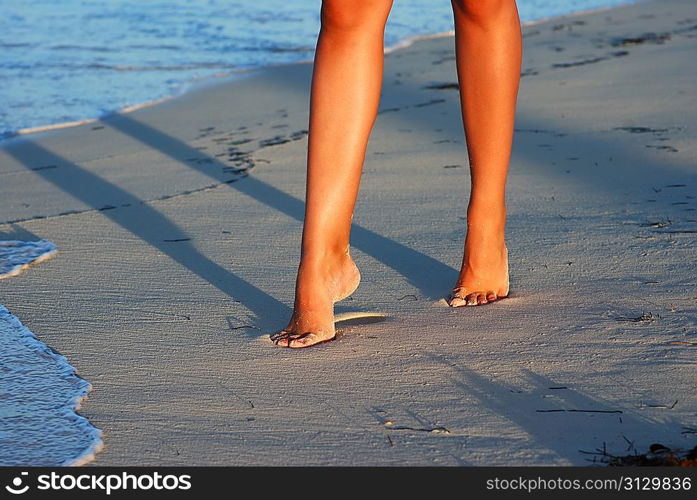 Women&acute;s sexy legs on the evening beach