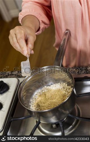 Women adding Wheat Germ to Oatmeal Breakfast while cooking on stove top