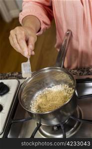Women adding Wheat Germ to Oatmeal Breakfast while cooking on stove top
