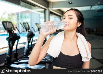 Women after exercise drink water from bottles and handkerchiefs in the gym.