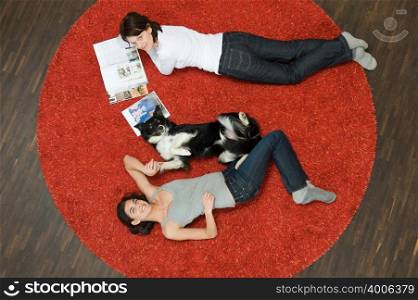 Women and dog lying on rug