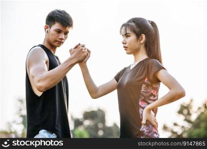 Women and men stand holding hands to exercise.