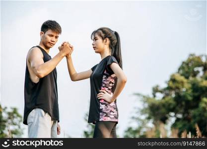 Women and men stand holding hands to exercise.