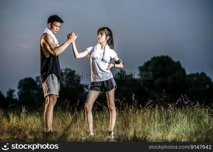 Women and men stand holding hands to exercise.