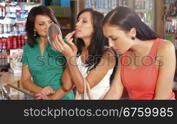 Women Applying Lip Gloss in Beauty Department