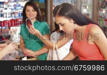 Women Applying Lip Gloss in Beauty Department