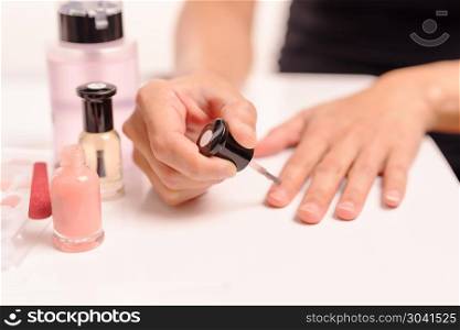 Women applying nail polish on white table with bottles of nail p. Women applying nail polish on white table with bottles of nail polish and remover, fashion and beauty concept