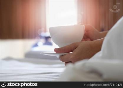 Women are drinking coffee on the bed in the morning.