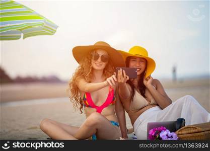 Women are taking photos and Selfie with friends on the sand beach in the summer.