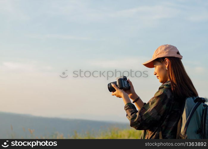 women asian with backpack taking a photo on view at sunrise seaside mountain peak