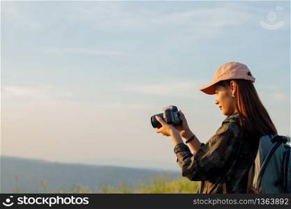 women asian with backpack taking a photo on view at sunrise seaside mountain peak