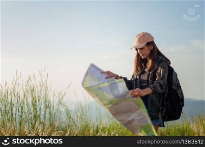 women asian with bright backpack looking at a map. View from back of the tourist traveler on background mountain, Female hands using smartphone,