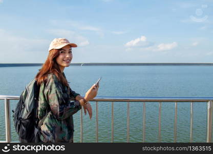 women asian with bright backpack looking at a map. View from back of the tourist traveler on background mountain, Female hands using smartphone,