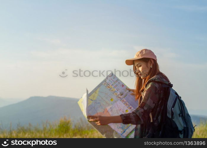 women asian with bright backpack looking at a map. View from back of the tourist traveler on background mountain, Female hands using smartphone, holding gadget