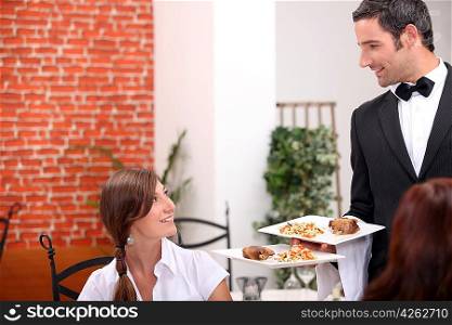 women at restaurant with waiter