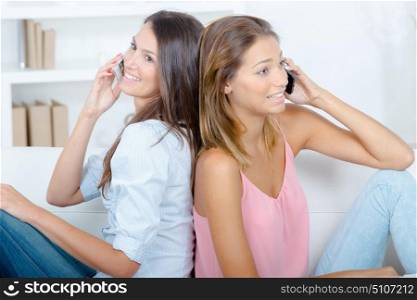 Women back to back using their cellphones