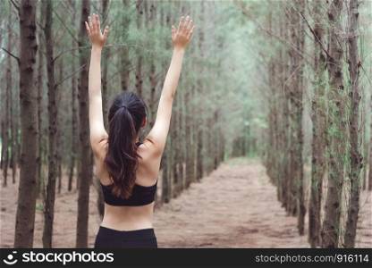 Women breathe fresh air in middle of pinewood forest while exercising. Workouts and Lifestyles concept. Happy life and Healthcare theme. Nature and Outdoors theme. Back view