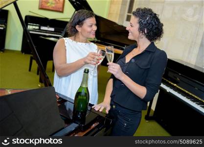 Women by pianos toasting with champagne