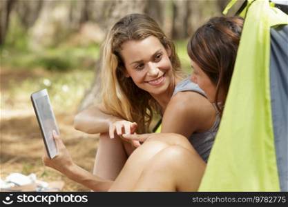 women checking tablet while in the tent