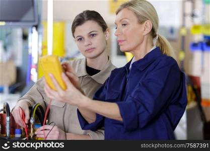 women checking voltage of a machine