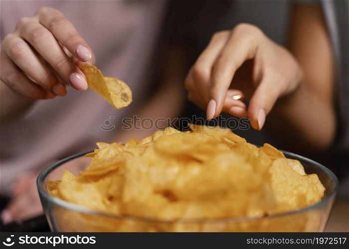 women couch watching tv eating chips close up. High resolution photo. women couch watching tv eating chips close up. High quality photo