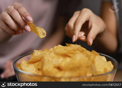 women couch watching tv eating chips close up. High resolution photo. women couch watching tv eating chips close up. High quality photo