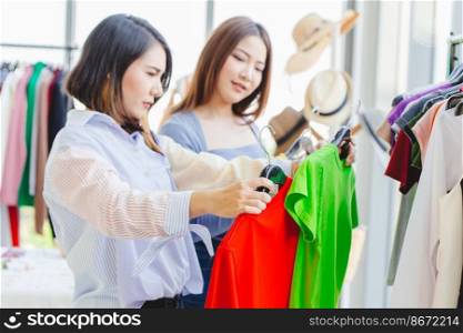 Women customer choosing clothes looking for new shirt in fashion shop with friend happy smile.
