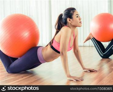 Women doing exercise with fit ball in gym group or yoga class. Healthy lifestyle concept.