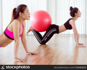 Women doing exercise with fit ball in gym group or yoga class. Healthy lifestyle concept.