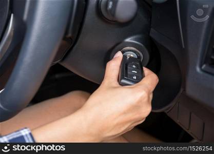 Women driver hand inserting car key and starting engine.