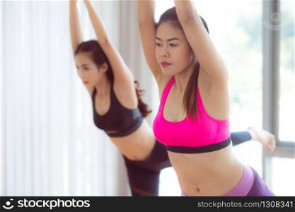 Women exercising yoga pose in fitness gym group class. Healthy lifestyle and wellness concept.