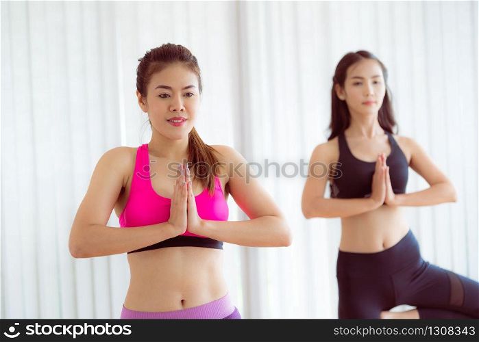 Women exercising yoga pose in fitness gym group class. Healthy lifestyle and wellness concept.