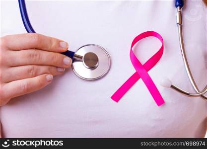 Women fight for health. Breast cancer tumor concept. Pink ribbon and blue stethoscope on female chest, closeup. Pink ribbon and stethoscope on female chest