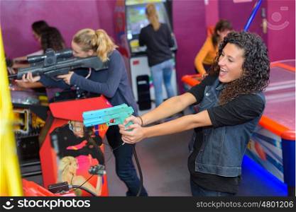 Women firing guns playing arcade game