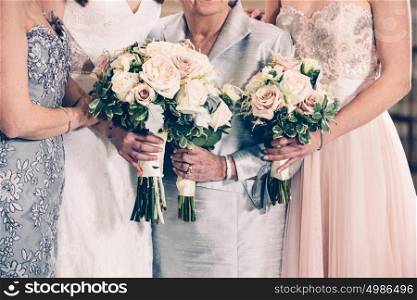 Women generation family and bride holding flowers bunches on wedding day.