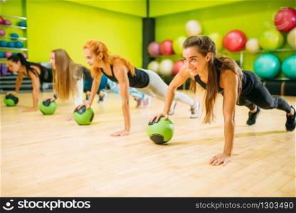 Women group with balls doing push up exercise, fitness workout. Female sport teamwork in gym. Fit class, aerobic