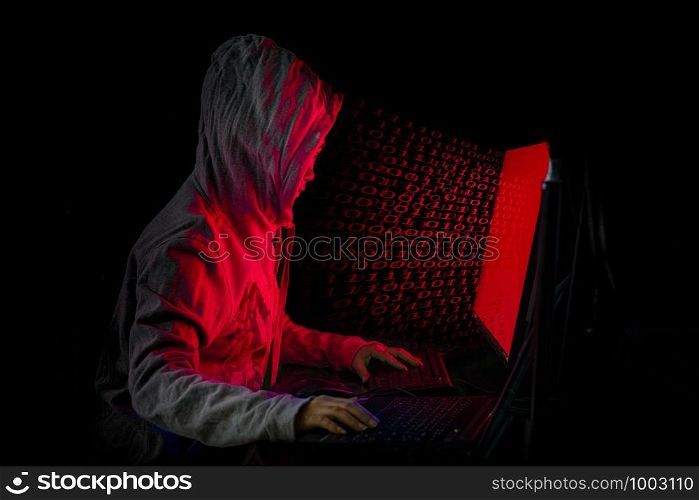 Women hacker breaks into government data servers and Infects Their System with a Virus at his hideout place has dark blue atmosphere, Lady hooded using laptop on binary code background